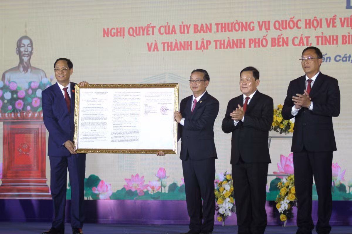 Phó Chủ tịch Quốc hội Trần Quang Phương (bìa trái) trao Nghị quyết về việc thành lập thành phố Bến Cát