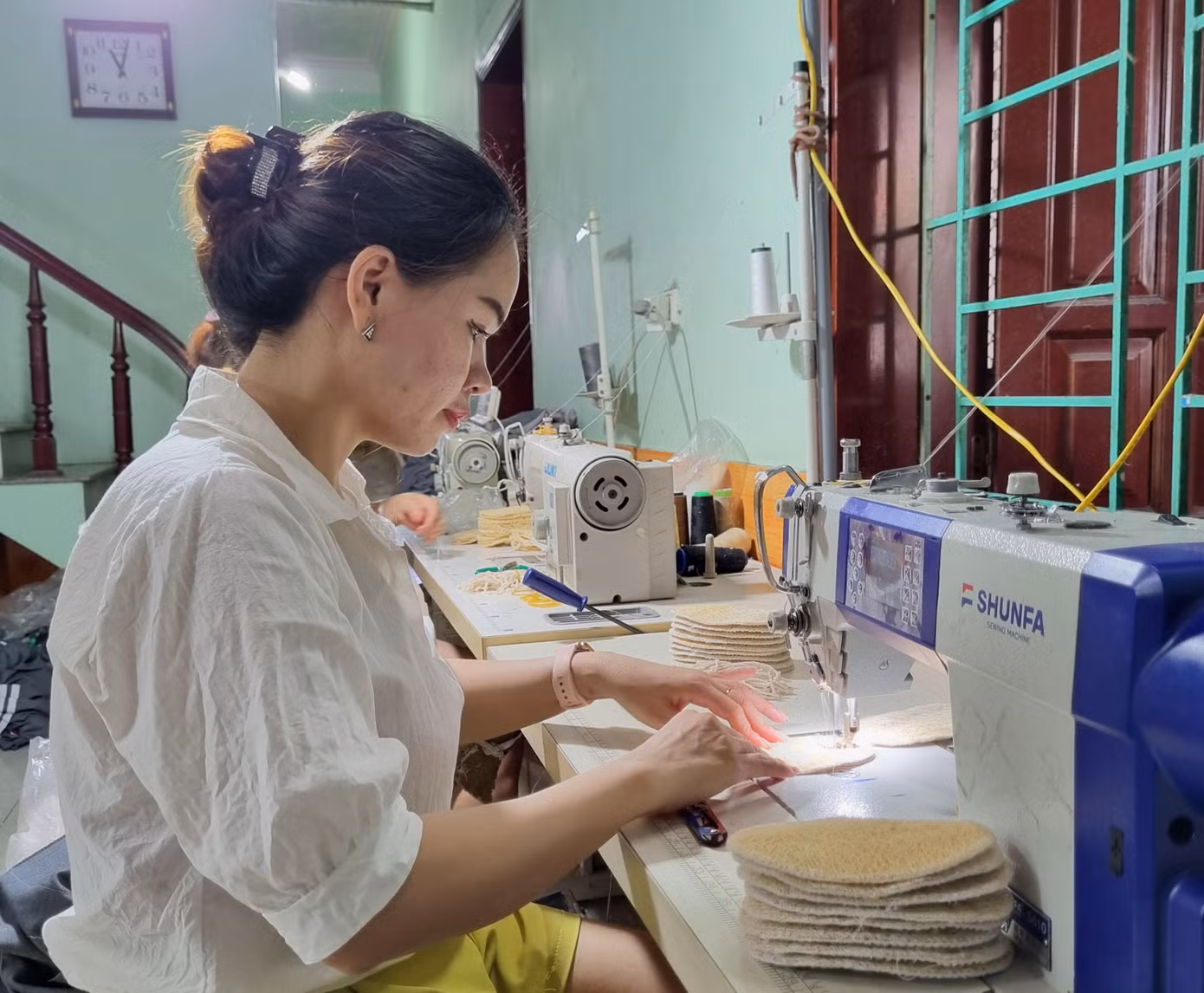 Tùy vào từng sản phẩm mà xơ mướp được cán dày hay mỏng. Với tiêu chí đặt ra là sản phẩm thân thiện môi trường nên khi sản xuất không dùng chất tẩy trắng hoặc ngâm hóa chất. - Ảnh: Công nhân may viền các sản phẩm từ xơ mướp.