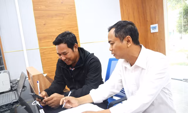 Cán bộ Trung tâm Phục vụ hành chính công xã Cư M’gar hướng dẫn anh A Kam (áo đen) cách nộp hồ sơ trực tuyến 