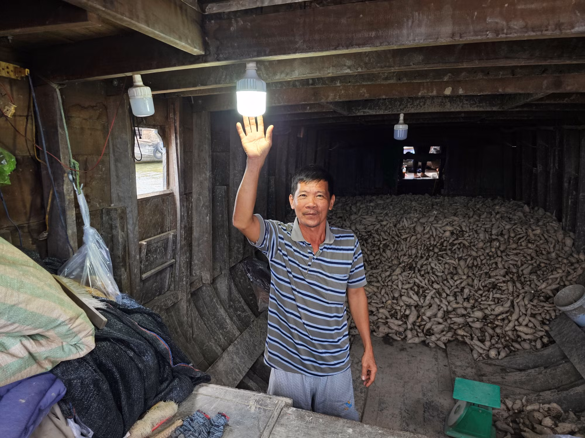Ông Lâm Văn Phong ở chợ nổi Cái Răng bên ánh đèn được thắp sáng từ năng lượng mặt trời. Ảnh: Hòa Hội.