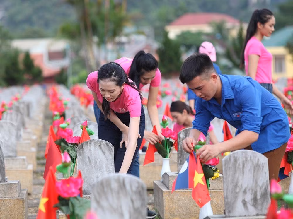 Ảnh 1: Các thí sinh Hoa hậu Việt Nam cùng ĐVTN Nghệ An chăm sóc nghĩa trang để chuẩn bị dâng 11.000 cây nến và nén nhang tại Nghĩa trang Việt - Lào ở Anh Sơn, Nghệ An. Ảnh 2: Một phần nghĩa trang khi nến và hương được thắp lên