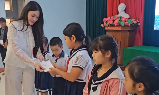Người đẹp Phùng Thị Hương Giang trao quà cho các em học sinh bị ảnh hưởng bởi lũ lụt.