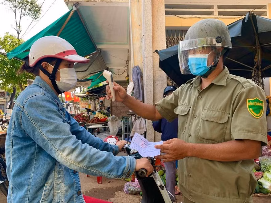 Người dân trước khi vào chợ đều phải xuất trình phiếu và được đo thân nhiệt. Ảnh: Nguyễn Ngọc